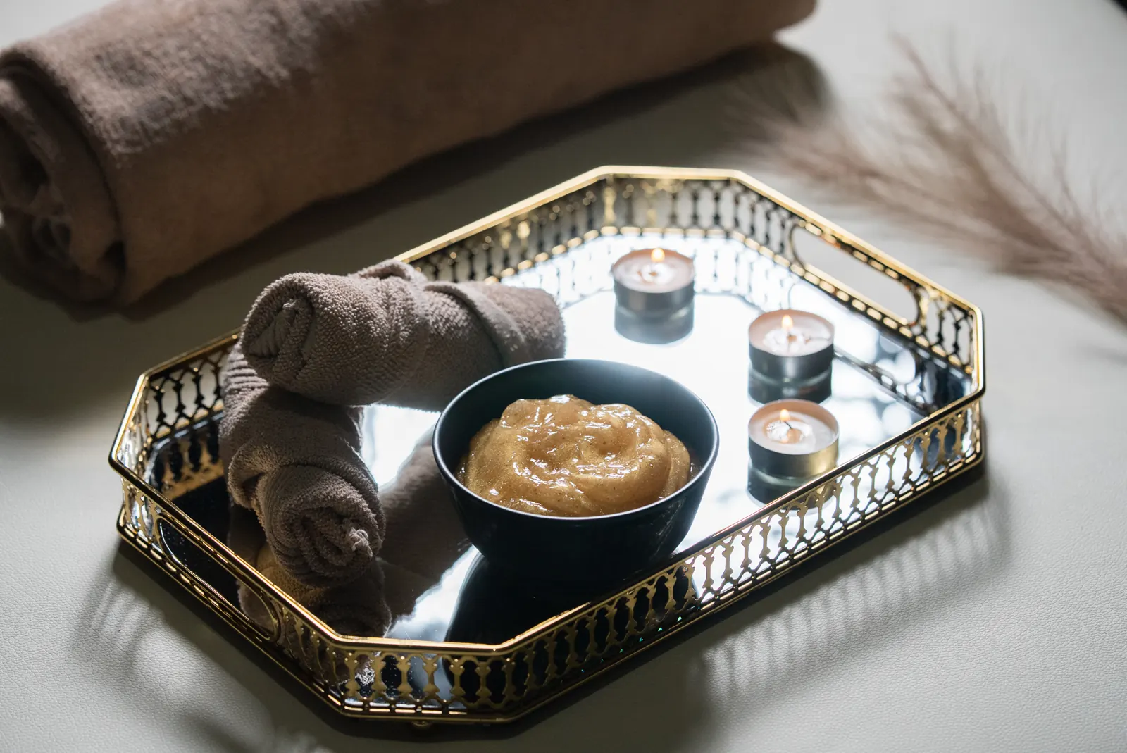 Golden tray with body scrub, candles and towel