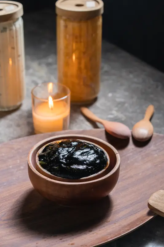 Black soap in a wooden bowl with candle